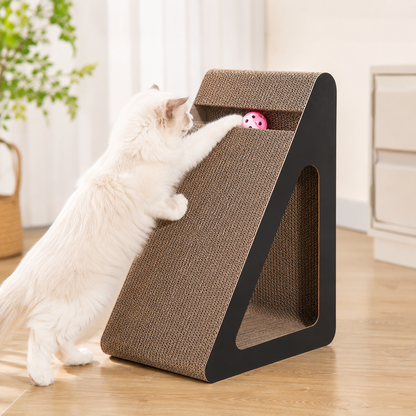 Chat blanc jouant avec la balle intégrée d’un griffoir incliné en carton pour chat d’intérieur.